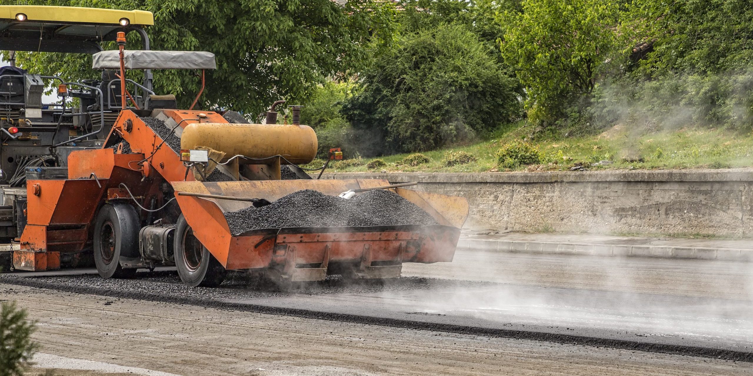 Asphalt paver machine makes a new road and repairing works. A paver finisher, asphalt finisher or paving machine placing a layer of asphalt. Repaving.