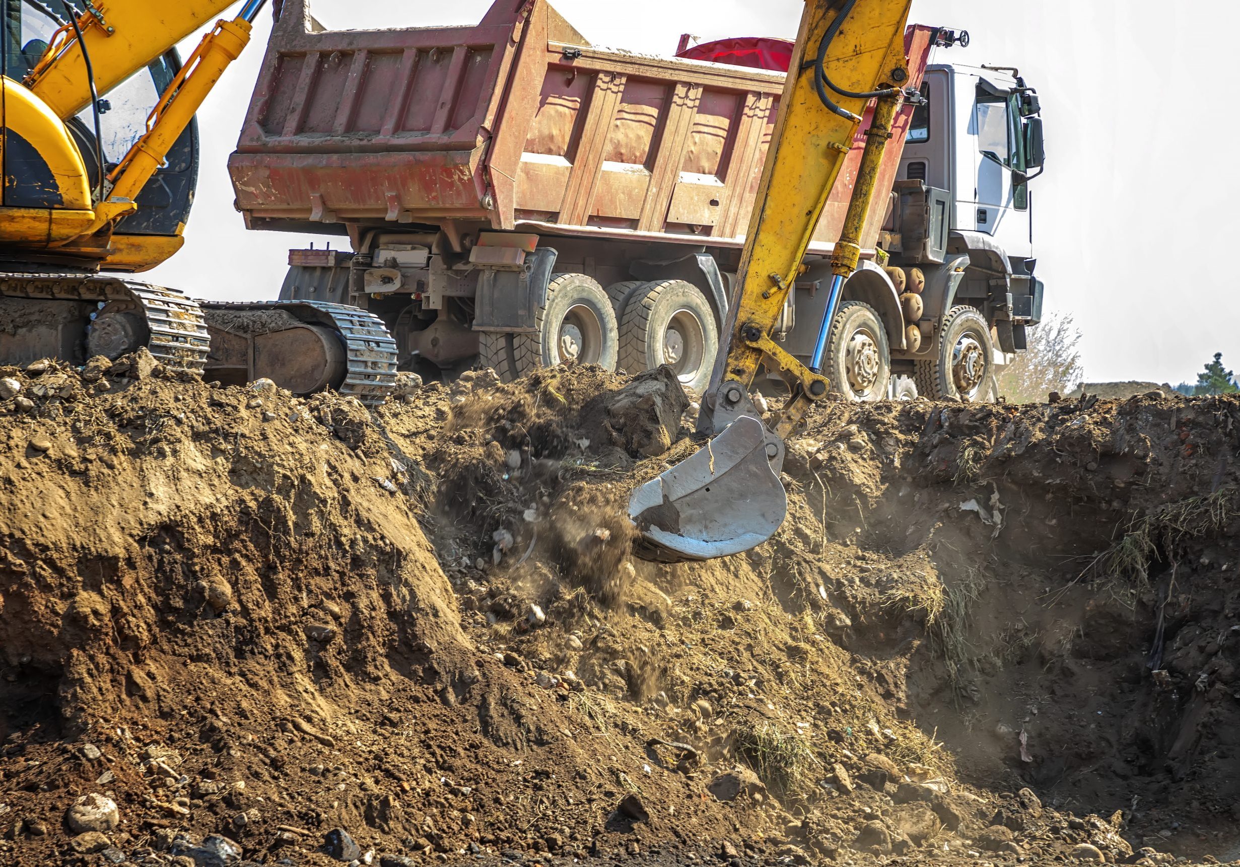 Excavator is loading excavation on the truck. Heavy construction equipment consisting of a boom, dipper or stick, bucket, and cab on a rotating platform.