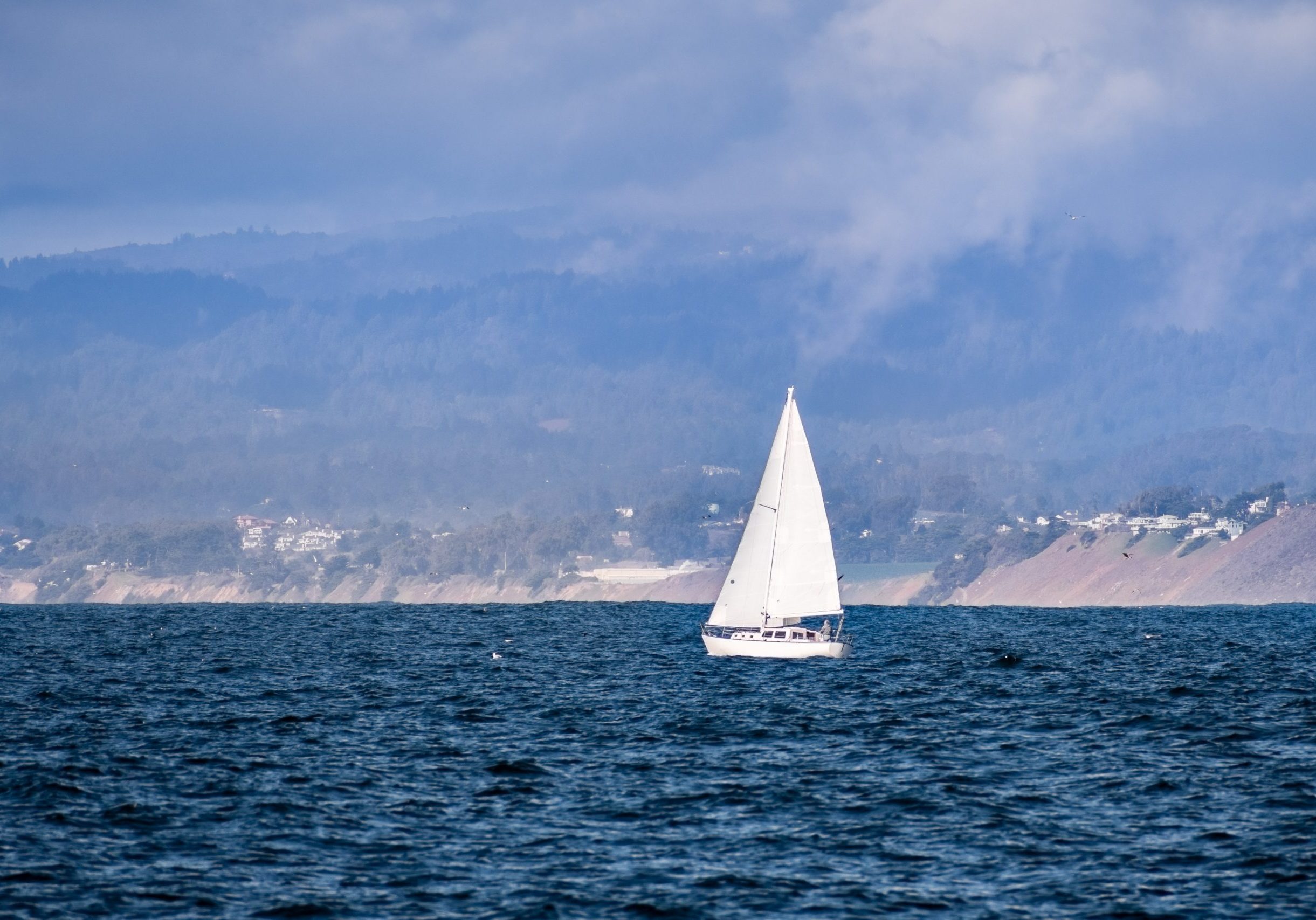 Sailboat close to the Pacific Ocean coastline near Moss Landing, Monterey Bay, California