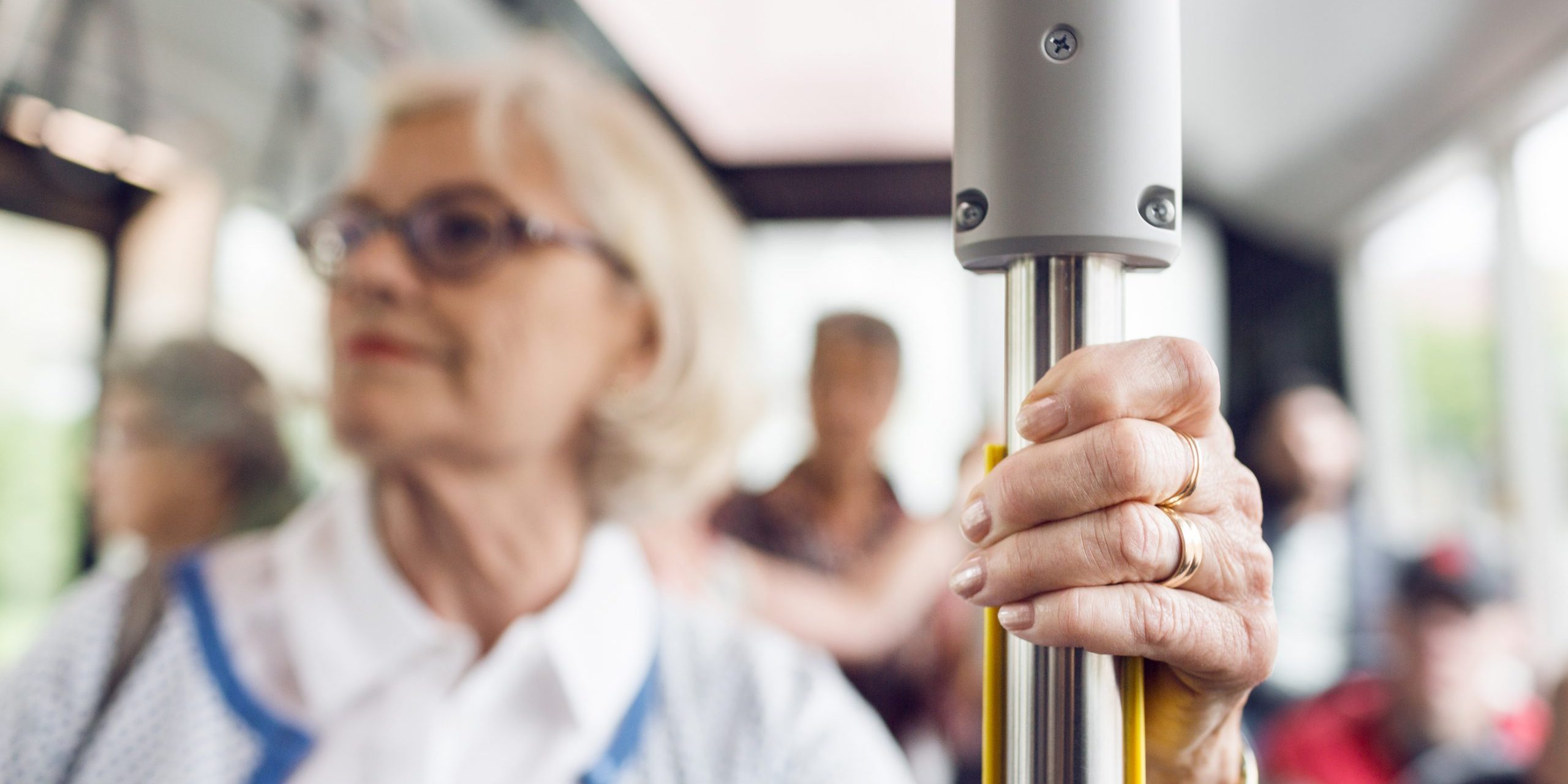 Senior woman holding handrail in bus